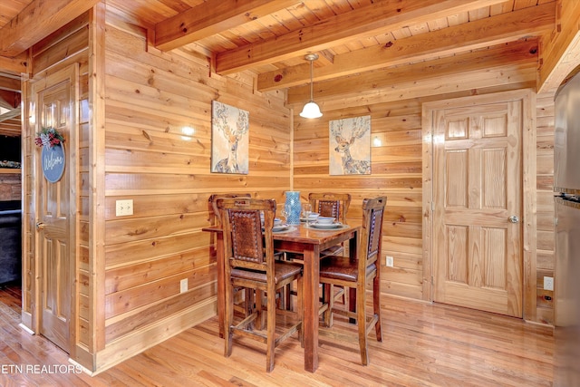 dining area with wood ceiling, beamed ceiling, wooden walls, and wood finished floors