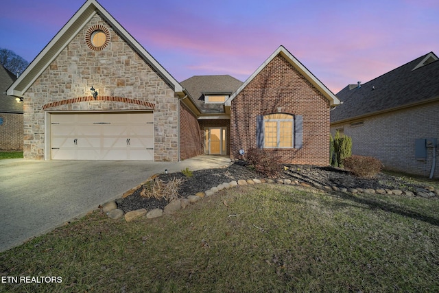 french country inspired facade with a garage, driveway, brick siding, and stone siding