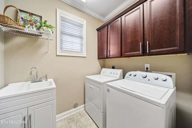 washroom with cabinet space, baseboards, ornamental molding, washing machine and clothes dryer, and a sink