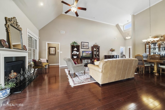 living area with visible vents, dark wood-type flooring, high vaulted ceiling, a warm lit fireplace, and ceiling fan with notable chandelier