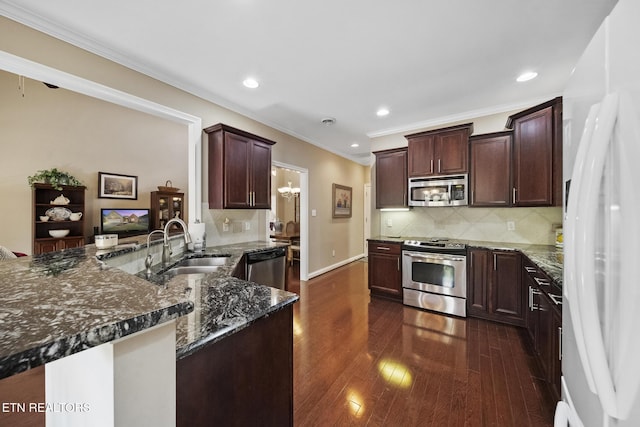 kitchen featuring dark stone counters, dark wood-type flooring, a peninsula, stainless steel appliances, and a sink