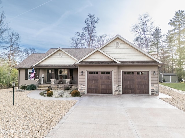 craftsman-style home with stone siding, covered porch, driveway, and a garage