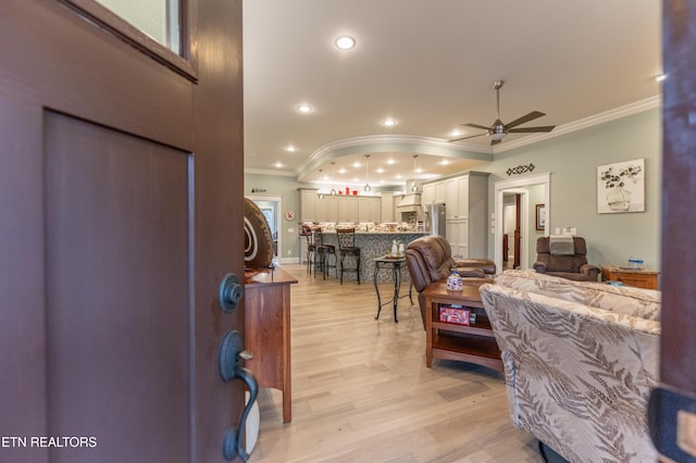 living room featuring ceiling fan, ornamental molding, light wood-style flooring, and recessed lighting