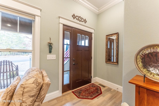 entrance foyer featuring ornamental molding, visible vents, light wood-style flooring, and baseboards