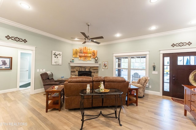 living room featuring ornamental molding, light wood-type flooring, a fireplace, and baseboards