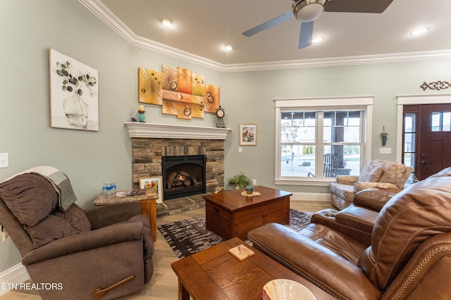 living area with light wood finished floors, a fireplace, ornamental molding, and a ceiling fan