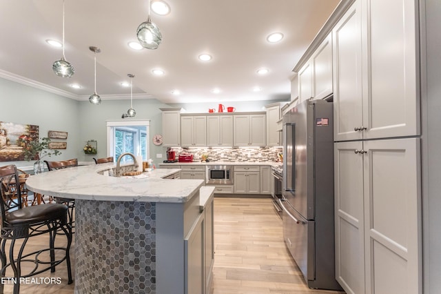 kitchen with appliances with stainless steel finishes, a breakfast bar area, decorative light fixtures, light stone countertops, and gray cabinets