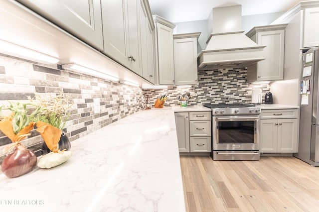 kitchen featuring stainless steel appliances, backsplash, custom exhaust hood, and gray cabinetry