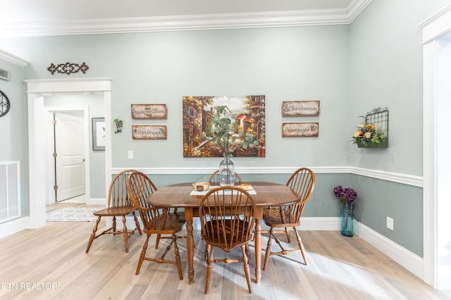 dining space featuring light wood-style floors, baseboards, visible vents, and ornamental molding