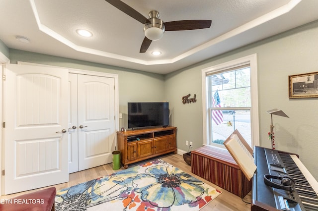 interior space featuring light wood-style flooring, a tray ceiling, ceiling fan, and recessed lighting