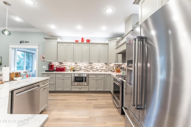 kitchen with premium appliances, light stone counters, pendant lighting, tasteful backsplash, and gray cabinetry