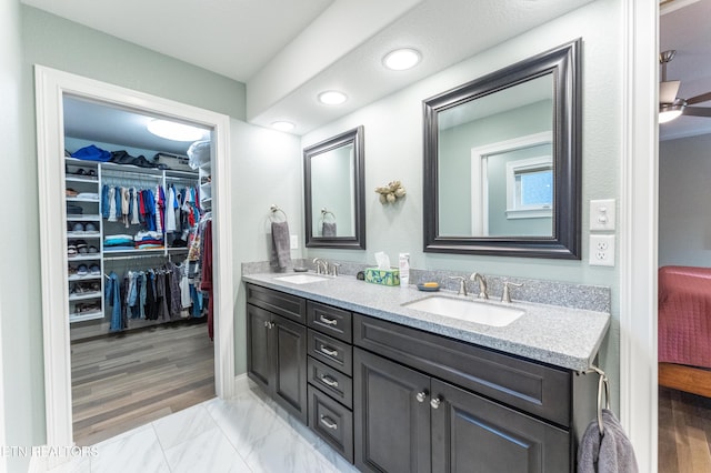 full bath featuring a walk in closet, marble finish floor, a sink, and double vanity