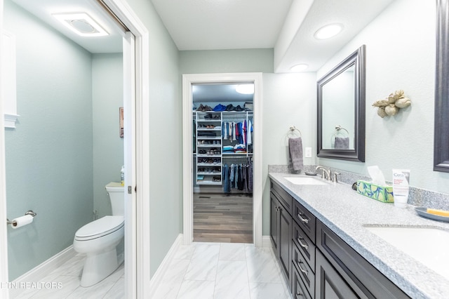 full bathroom featuring a sink, a spacious closet, toilet, and double vanity