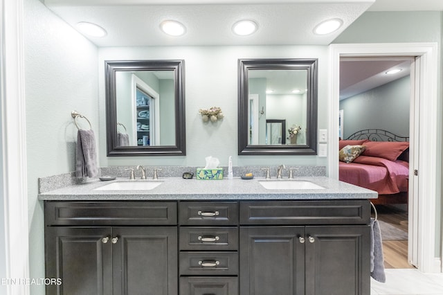 ensuite bathroom featuring a sink, double vanity, and connected bathroom