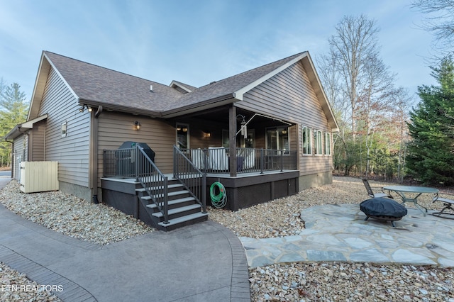 rustic home with a fire pit, covered porch, a shingled roof, stairs, and a patio area