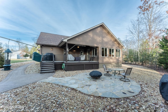 rear view of house with a fire pit, a shingled roof, and a patio area