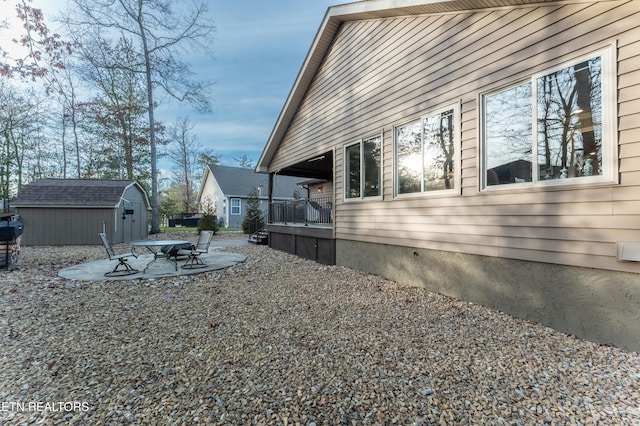 view of side of property with an outbuilding, a shed, and a patio area