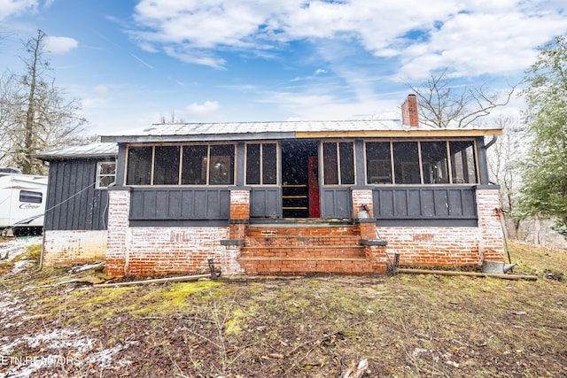 view of front of home featuring a sunroom, metal roof, and a chimney