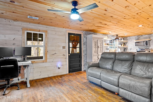 living area featuring wooden ceiling, ceiling fan, wood walls, and wood finished floors