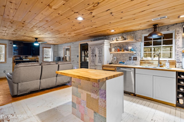 kitchen with a sink, wooden counters, stainless steel dishwasher, light wood-type flooring, and decorative light fixtures