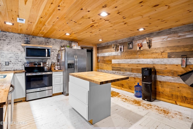 kitchen with wooden ceiling, stainless steel appliances, a kitchen island, white cabinets, and wooden counters