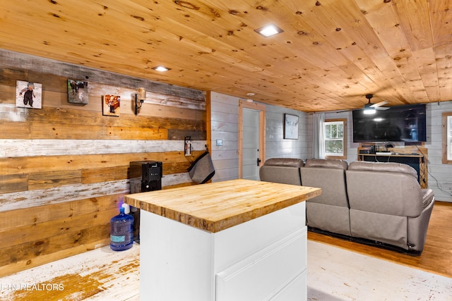 kitchen with wood walls, wood ceiling, wooden counters, and open floor plan