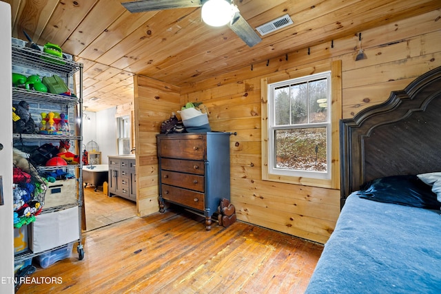 bedroom with wooden ceiling, visible vents, wooden walls, and wood finished floors