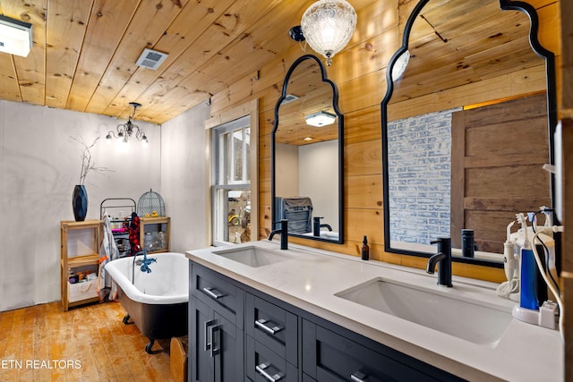 bathroom with a soaking tub, wooden ceiling, and a sink