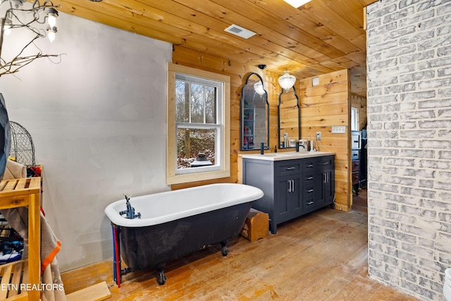 bathroom with a soaking tub, visible vents, vanity, wood finished floors, and wooden ceiling