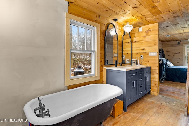 full bathroom featuring wooden walls, wood finished floors, wood ceiling, a soaking tub, and double vanity