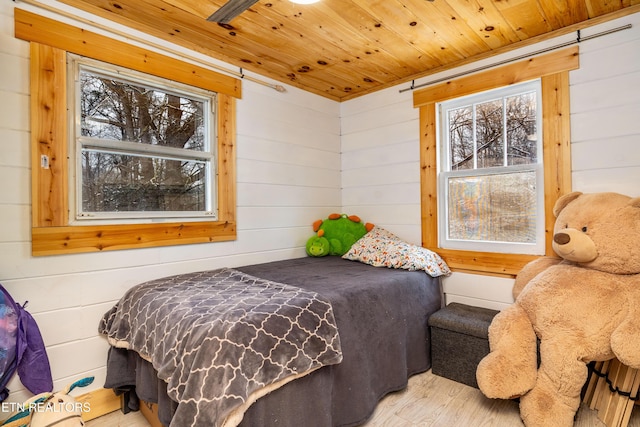 bedroom with wood walls, wooden ceiling, and light wood-style floors