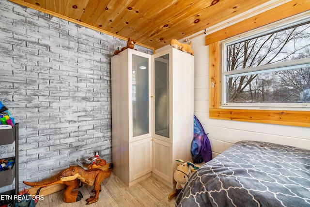 bedroom with wood ceiling, light wood finished floors, and brick wall