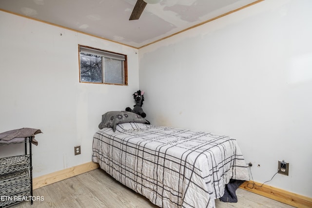 bedroom with baseboards, ceiling fan, wood finished floors, and crown molding