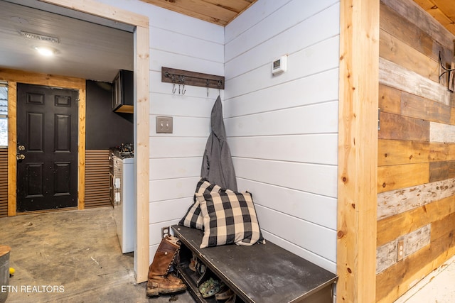 mudroom with washer / dryer, wooden walls, visible vents, and unfinished concrete floors