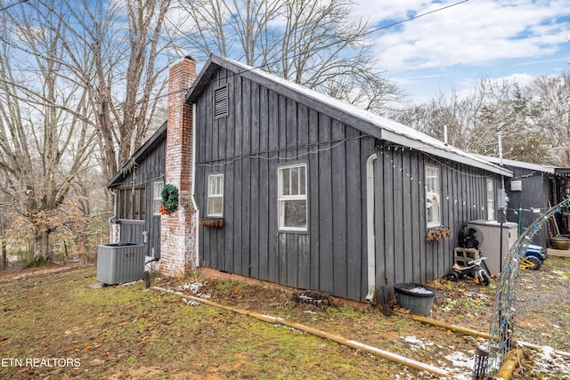 view of side of home featuring a chimney and central AC unit