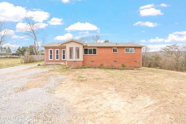 view of front of home featuring crawl space, brick siding, driveway, and fence