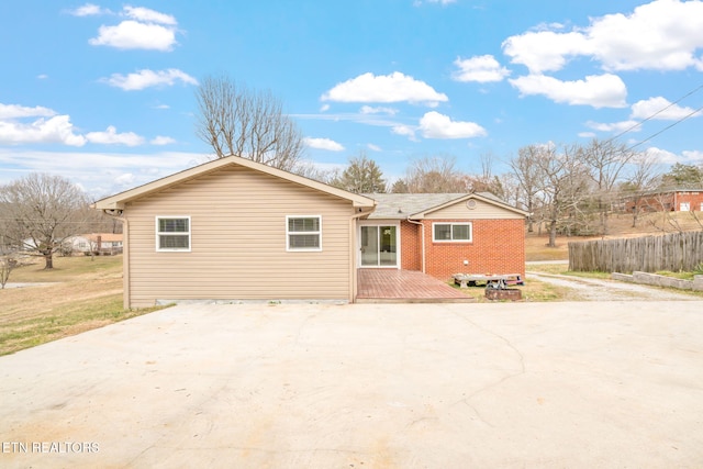 ranch-style house featuring concrete driveway, brick siding, and a wooden deck