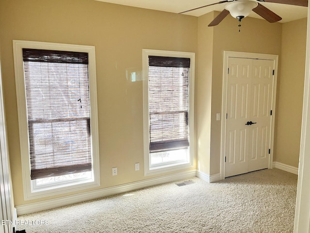 interior space with light carpet, ceiling fan, visible vents, and baseboards