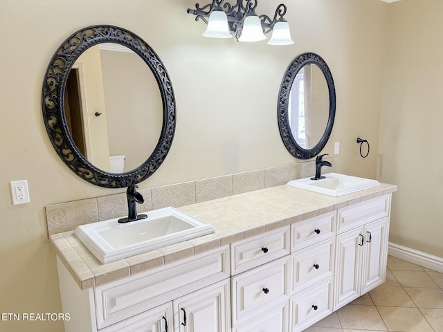 bathroom with double vanity, tile patterned flooring, baseboards, and a sink