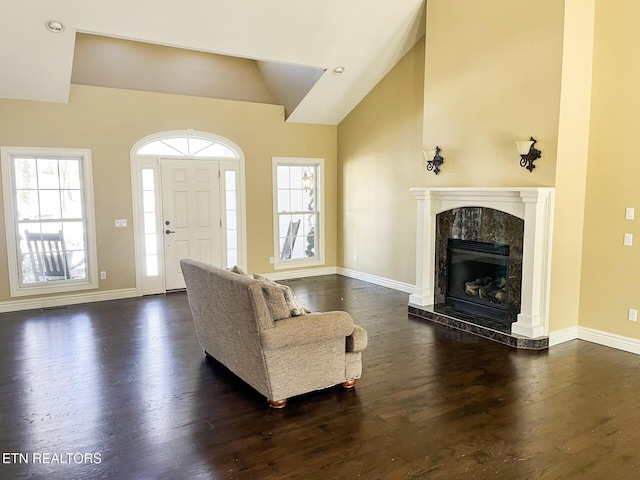 living room with high vaulted ceiling, a premium fireplace, dark wood finished floors, and baseboards