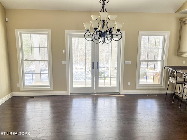 unfurnished dining area featuring baseboards, visible vents, and dark wood finished floors