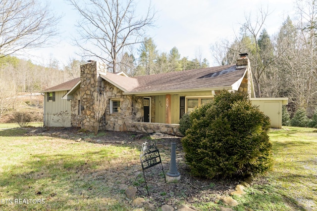 view of front of house with board and batten siding, stone siding, a chimney, and a front lawn