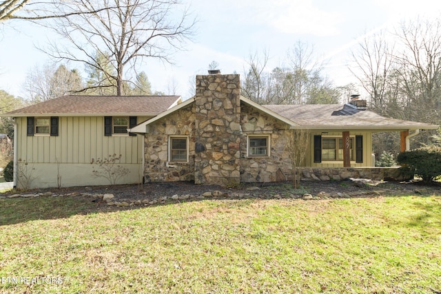 view of front of house featuring stone siding, a chimney, covered porch, board and batten siding, and a front yard