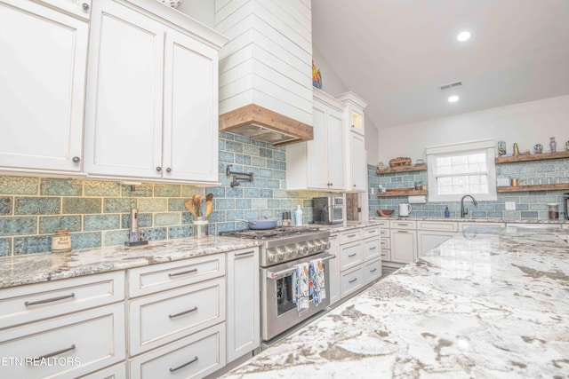 kitchen featuring open shelves, stainless steel range, backsplash, and white cabinets