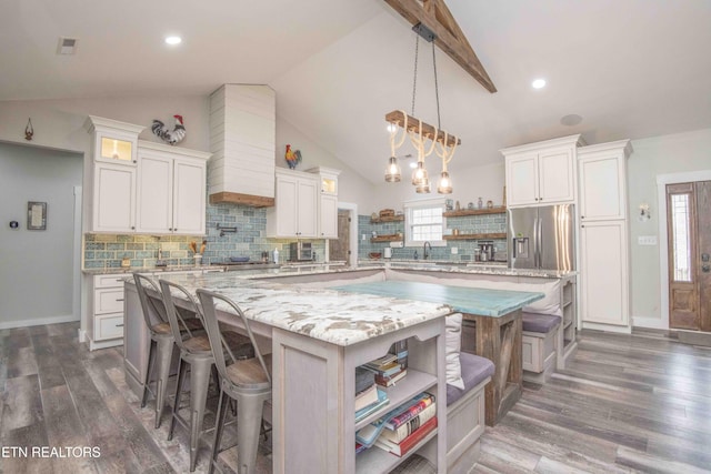 kitchen with stainless steel fridge with ice dispenser, a large island, a kitchen bar, and open shelves