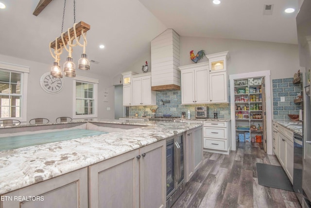kitchen featuring dark wood finished floors, lofted ceiling, hanging light fixtures, decorative backsplash, and glass insert cabinets