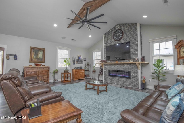 living area with a fireplace, lofted ceiling, visible vents, ceiling fan, and wood finished floors