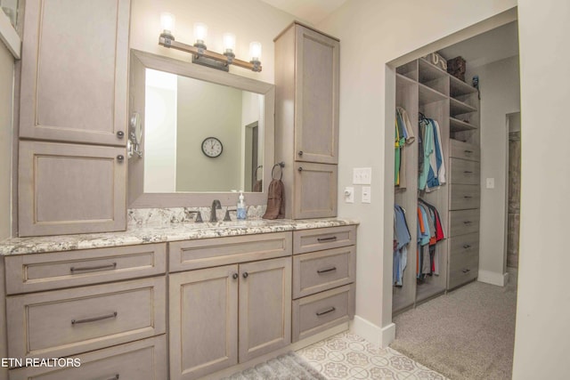 bathroom featuring a spacious closet, baseboards, and vanity