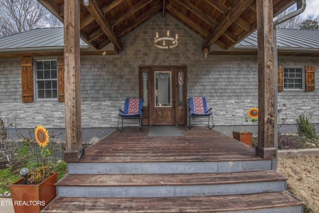 doorway to property with stone siding, a standing seam roof, metal roof, and a wooden deck