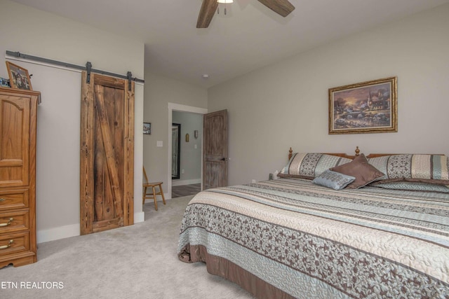 bedroom with light carpet, a barn door, baseboards, and ceiling fan